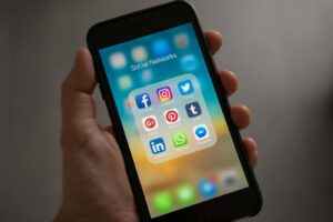 Un smartphone affichant diverses icônes de médias sociaux tenu dans une main, présentant des applications de communication modernes.